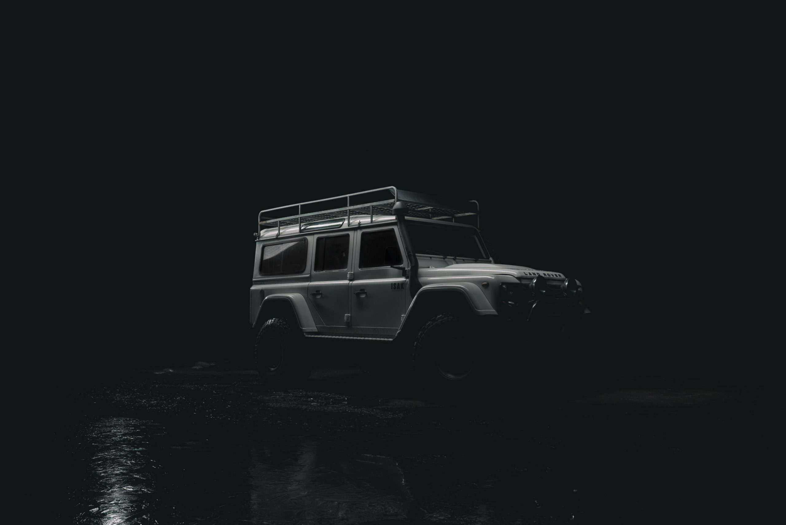 Defender vs Wrangler — Land Rover Defender driving through mountain landscape